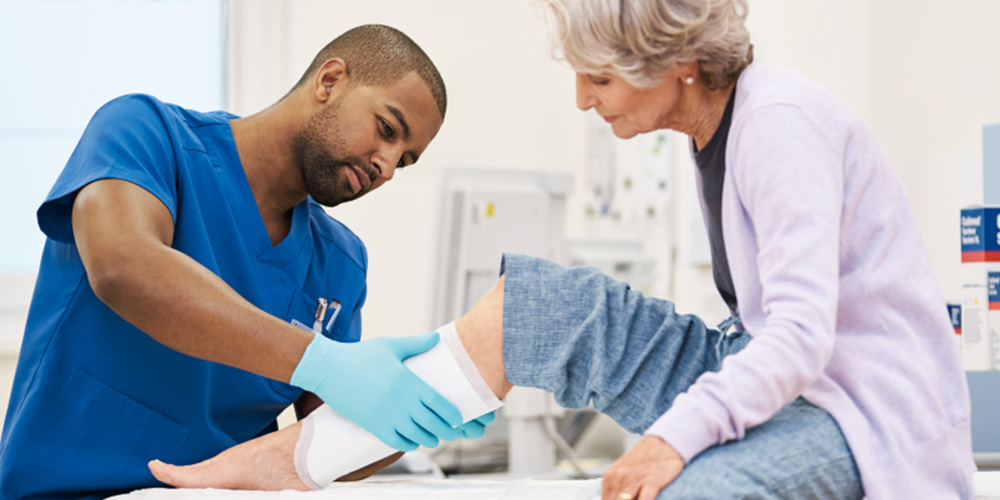 A male nurse exchanging the dressing of a patient. A male nurse exchanging the dressing of a patient.